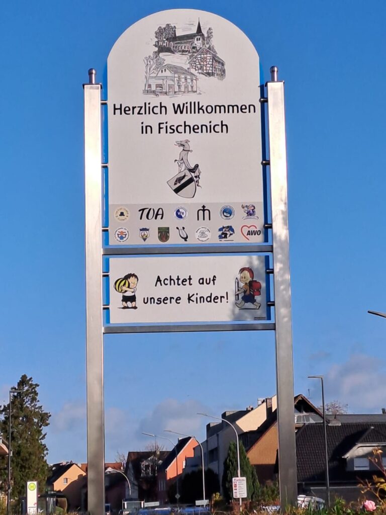 Das Bild zeigt das Ortseingangsschild mit dem Text Herzlich Willkommen in Fischenich. 